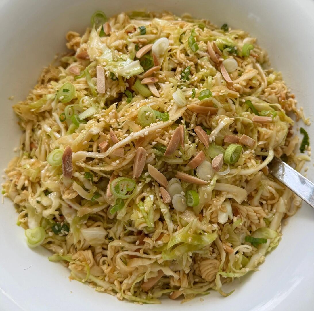 Cold sesame-cabbage crunch (8 things, feeds 4, under 10 min, no beans) → shred half a green cabbage and two carrots; whisk tahini, soy, a squeeze of lime, a little honey, some cold soaked noodles even and hot water to loosen; toss, top with whatever nuts or seeds are in the drawer. It costs pocket change and asks nothing of the oven. No one at your table goes hungry because the week tried to break you.